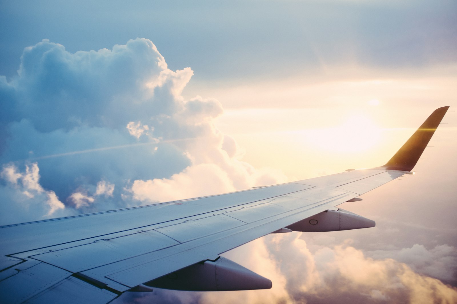 Aircraft wing above soft clouds at sunrise